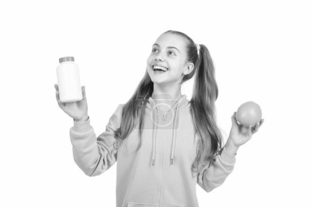 Téléchargez les photos : Enfant heureux choisir entre les fruits d'orange et la pilule de vitamine dans une bouteille de pot isolé sur blanc, médecine. - en image libre de droit