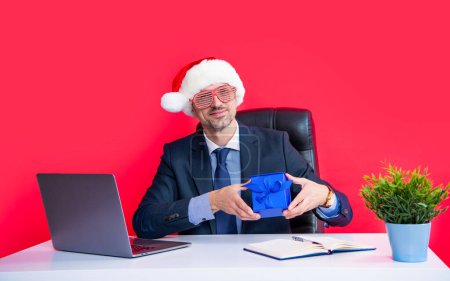 Téléchargez les photos : Heureux homme mature porter rouge santa claus chapeau et lunettes de fête tenir boîte cadeau. - en image libre de droit