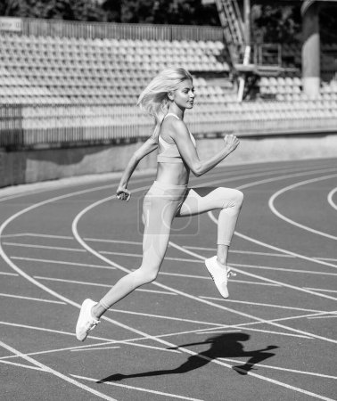 Téléchargez les photos : Femme athlétique en tenue de fitness courir sur le stade, le sport. - en image libre de droit
