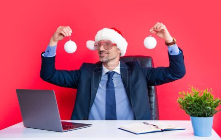 Téléchargez les photos : Gai homme mature porter rouge santa claus chapeau et lunettes de fête tenir décoration de Noël. - en image libre de droit