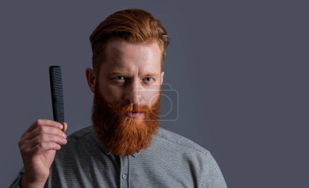 hairdresser man hold comb or hairbrush isolated on grey. hairdresser man with comb or hairbrush. man hairdresser holding comb or hairbrush in studio. man with comb or hairbrush. hairdresser concept.