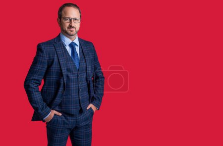 Foto des Geschäftsmannes im Anzug, Kopierraum. Reifer Geschäftsmann auf rotem Hintergrund. Geschäftsmann im Studio. Geschäftsmann trägt Sakko und Krawatte.