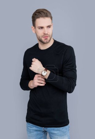young man with stubble in watch isolated on grey background. caucasian man having stubble. stylish watch. man with stubble wear wrist watch in studio.