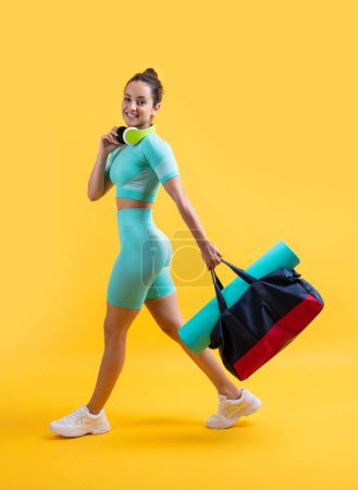 Photo for Glad fitness woman in sportswear walk with sport bag in studio. fitness woman in workout sportswear isolated on yellow background. fitness and sportswear. - Royalty Free Image