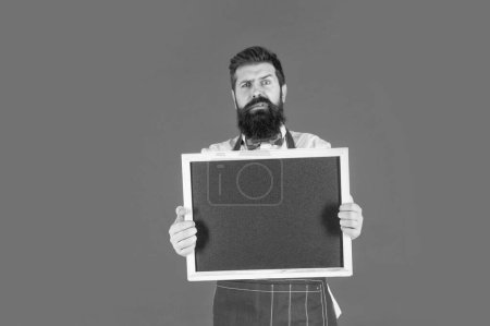 Photo for Being nervous on the opening day. Anxious bearded man hold school blackboard. Barbershop price board. Barbershop advertising, copy space. - Royalty Free Image