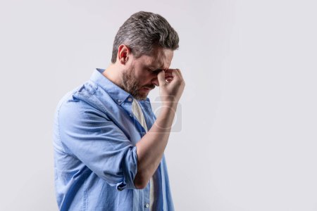 mature man with headache and migraine in studio with copy space. photo of man with migraine headache. man with headache or migraine wear shirt. man with headache or migraine isolated on grey