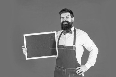 Photo for Promotional advertising. Winking man smile holding promo blackboard. Advertising promotion. School chalkboard for advertisement. Advertise with us, copy space. - Royalty Free Image