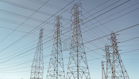 Foto de Voltage transmission on electric tower. high-voltage. powerful substation on blue sky backdrop with nobody. electrical power lines. pylon producing energy. - Imagen libre de derechos