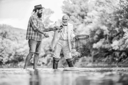 Photo for Two fishermen. successful catch. granddad and drandson fishing. retired businessman. male friendship. Good profit. hobby and recreation. Success. fisher celebrate retirement. good production. - Royalty Free Image