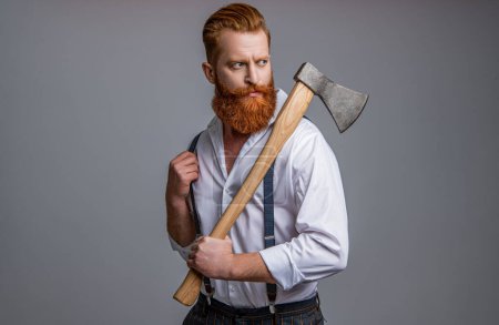 handsome brutal man with axe isolated on grey. brutal man with axe in studio. brutal man with axe on background. photo of brutal man with axe.