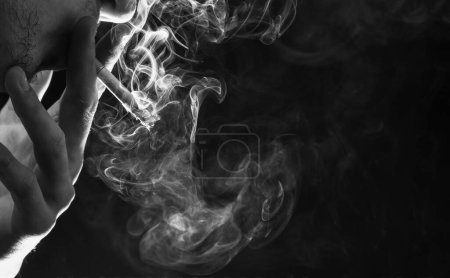 Smoke and choke. Cigarette smoke dark background. Steaming cigarette in male hand. Tobacco smoking. Nicotine addiction. copy space.