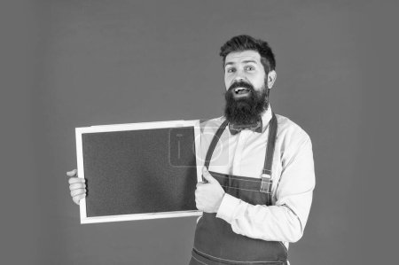 Photo for Happy bearded man give thumbs up approval sign hand gesture holding school chalkboard red background copy space, barber school. - Royalty Free Image