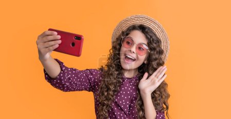 Foto de Happy girl with curly hair taking selfie on phone. hello. - Imagen libre de derechos