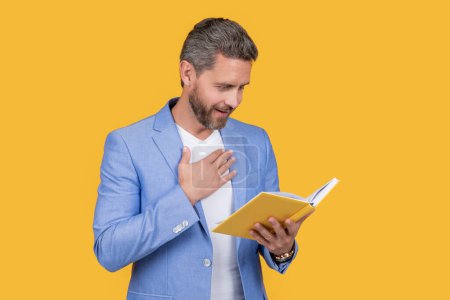 studio shot of sincerely man reader reading book. photo of man reader reading book. man reader reading book isolated on yellow background. man reader reading book in jacket.