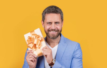 Téléchargez les photos : Happy guy with gift box for holiday. photo of guy holding occasion gift box. guy hold gift box isolated on yellow background. guy hold gift box in studio. - en image libre de droit
