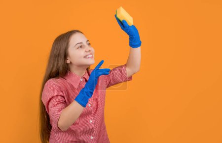 positive child in rubber gloves with sponge on yellow background.