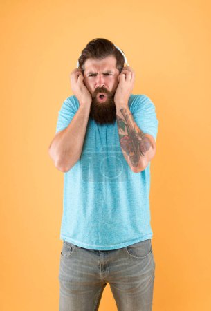 Photo for Bearded guy dislike music. Irritating sound. Man listening music wireless headphones. Equalizer settings. Awful sound. Hipster listen broken headphones music gadget. Hateful song. Music taste. - Royalty Free Image