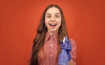 amazed child in rubber gloves with spray bottle on red background.