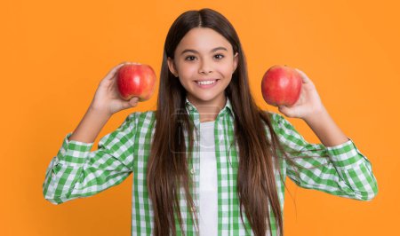 Téléchargez les photos : Cheerful child with apple on yellow background. - en image libre de droit