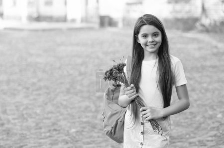 Téléchargez les photos : Heureux fille avec sac d'école tenir des fleurs pour septembre 1. espace de copie. - en image libre de droit