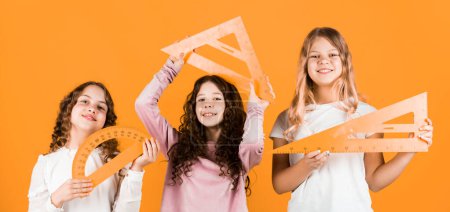 Photo for School friendship. Group studying. Teamwork and help. Developing cognitive skills. Study together. Clever kids. Education concept. School students learning geometry. Girls with triangle ruler. - Royalty Free Image