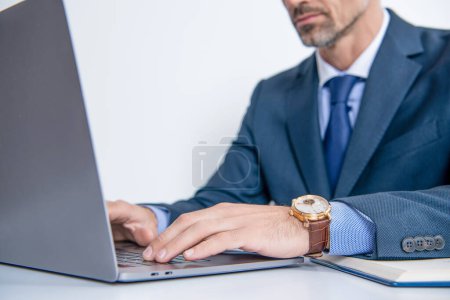Mann tippt in Armbanduhr online auf Laptop-Tastatur, selektiver Fokus.