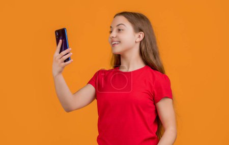 Foto de Happy teen child with smartphone on yellow background. - Imagen libre de derechos