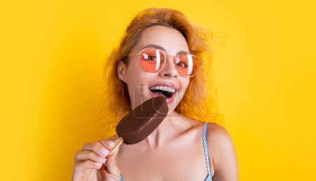 Foto de Cara feliz de mujer comiendo helado en el estudio. mujer con helado en el fondo. foto de la mujer con helado en verano. mujer con helado aislado en amarillo. - Imagen libre de derechos