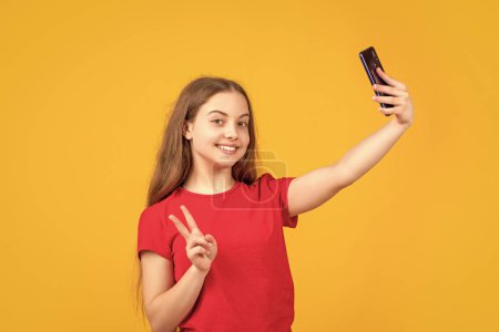 Téléchargez les photos : Enfant heureux avec smartphone sur fond jaune. paix. - en image libre de droit