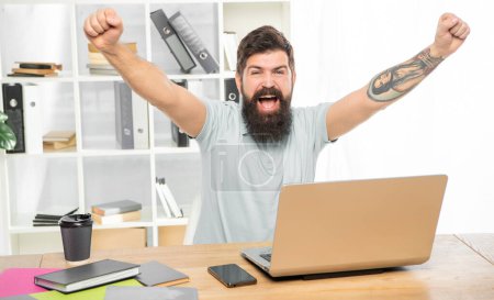 Photo for Excited man happy screaming making winning gesture at laptop in office, achievement. - Royalty Free Image
