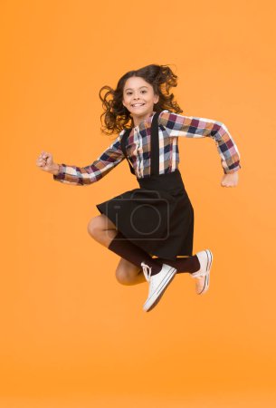 Day full of fun. Happy child enjoy happiness. Energetic girl in midair yellow background. Childhood and happiness. School holidays. Free time. Happiness concept. Happiness is habit.