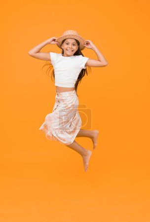 Feel so free. barefoot kid feel freedom. full of happiness. summer kid fashion. little girl jumping high on yellow background. energetic kid on vacation. super active child jump in straw hat.