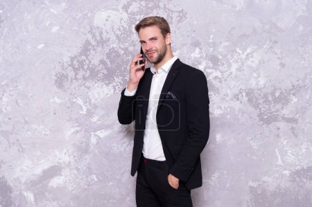 Photo for Smiling business man talk on background. photo of business man talk on phone wear suit. successful business man talk on phone isolated on grey. business man talk on phone in studio. - Royalty Free Image
