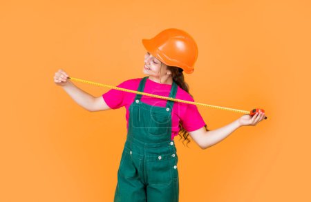 Photo for Smart professional. building and construction. concept of repair. Little girl use measuring tape. engineer. happy child hold tape measure. kid builder wear helmet. teen girl in hard hat and uniform. - Royalty Free Image