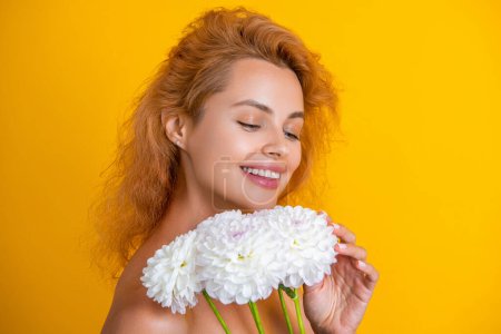 Smile of woman beauty with flowers isolated on yellow. woman beauty with flowers in studio. woman beauty with flowers on background. photo of woman beauty with chrysanthemum flowers.