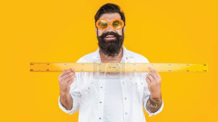 happy school man measure with ruler in studio. school man measure with ruler on background. photo of school man measure with ruler. school man measure with ruler isolated on yellow.