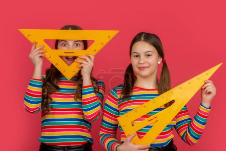 Photo for Smiling school girls hold math tool of triangle. - Royalty Free Image