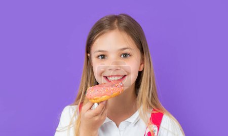 Teen girl eating yummy donut isolated on purple. teen girl with yummy donut in studio. teen girl with yummy donut on background. photo of teen girl with yummy donut.