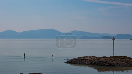 Photo for Standup paddleboarders paddleboarding on sea or lake. People paddleboarding on paddleboard. Sup. Standup paddleboarding. Water sport activity. Paddleboarding. Adventure. - Royalty Free Image