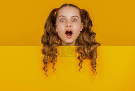 Photo for Amazed child with blank yellow paper with copy space for advertisement. - Royalty Free Image