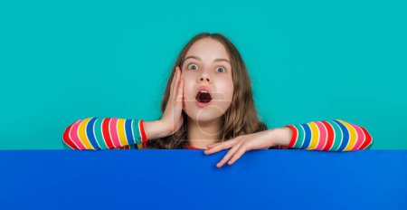 Photo for Shocked child with blank blue paper with copy space for advertisement. - Royalty Free Image