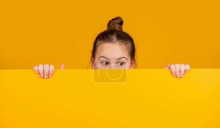 Photo for Kid hiding behind blank yellow paper with copy space for advertisement. - Royalty Free Image