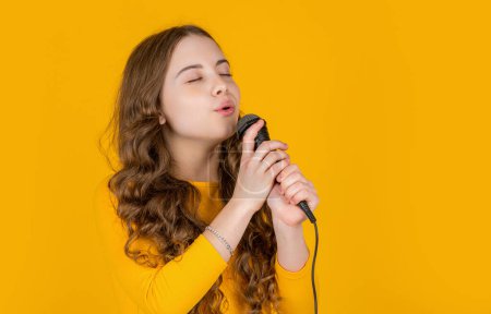 Foto de Musical adolescente chica con micrófono en amarillo fondo. - Imagen libre de derechos