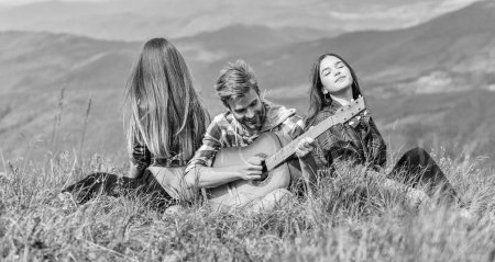 Photo for Melody of nature. Hiking tradition. Friends hiking with music. Nothing but friends and guitar. People relaxing on mountain top while handsome man playing guitar. Hiking entertainment. Peaceful place. - Royalty Free Image