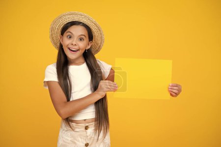 Photo for Amazed teen girl hold empty advertisement paper with copy space on yellow background. - Royalty Free Image