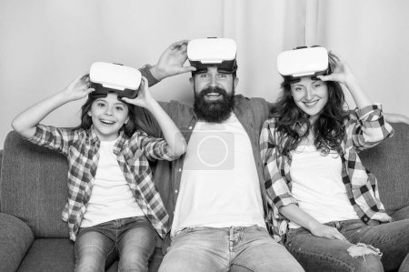 Foto de Happy parents with kid girl use modern technology at home. mom dad and daughter. digital future and innovation. modern life. father mother and child wireless VR glasses. virtual reality family. - Imagen libre de derechos