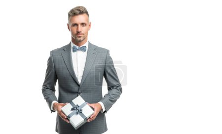 Téléchargez les photos : Homme d'affaires en costume bleu noeud papillon tenir boîte cadeau isolé sur blanc avec espace de copie. - en image libre de droit