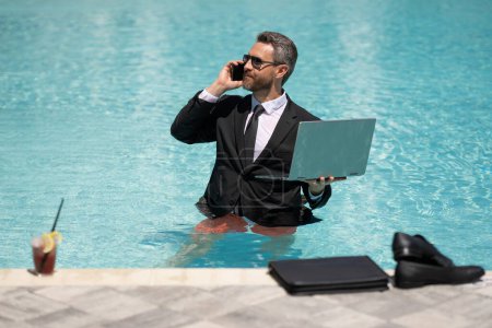 cheerful business manager work in summer at swimming pool. business manager work in summer has phone call. photo of business manager wearing suit work in summer pool. business manager work in summer.