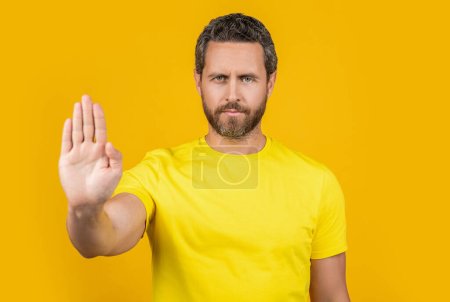 man express stop rejection in studio, selective focus. photo of man show stop rejection. man show stop rejection isolated on yellow. man showing stop rejection on background.