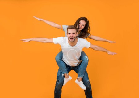 Spread your wings and fly away. Happy woman enjoy riding piggyback on guy. Couple in love having fun. Enjoy every moment.